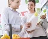 Two young women holding detergent in a supermarket