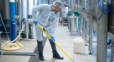 Professional industrial cleaner in protective uniform cleaning floor of food processing plant. Achieve remarkable heavy-duty cleansing, degreasing and disinfectant performance from Nouryon’s extensive portfolio of products – ranging from high alkaline, solvent and acid-based formulations to all-purpose hard surface cleaners